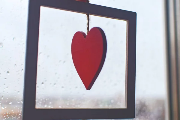 Red heart on a rope on a window covered with rain drops. — 图库照片