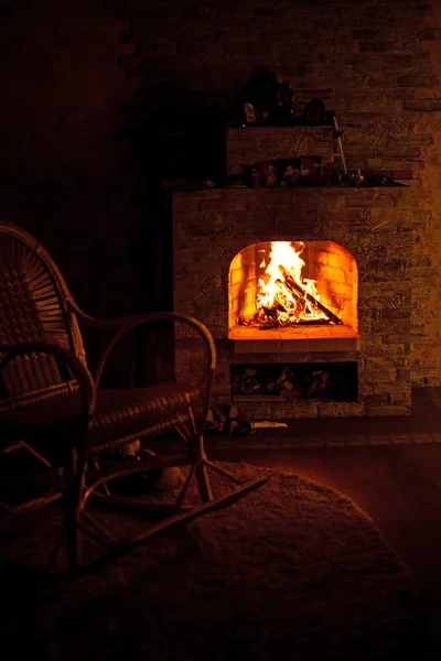 Köy evinde şöminenin yanında sallanan sandalye. Şöminede sıcak ateş.
