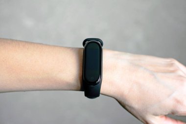 Bir kızın elinde siyah fitness takip cihazı. Spor eğitimi için spor bilekliği..