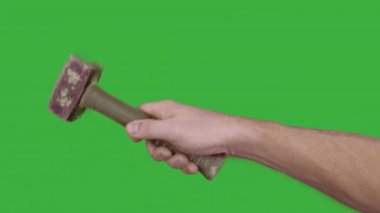 Yeşil arka planda çekiç tutan kişinin kırpılmış görüntüsü.