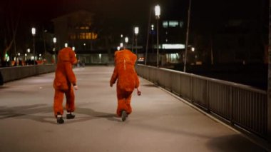Gece vakti köprüde yürüyen komik kostümlü insanların arka görüntüsü. Solothurn, İsviçre