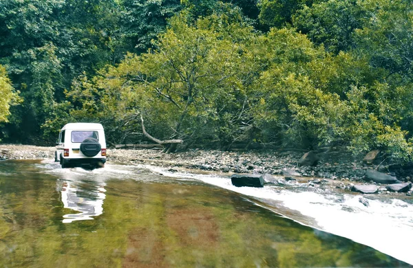 a jeep crossing river between the forest in Goa India
