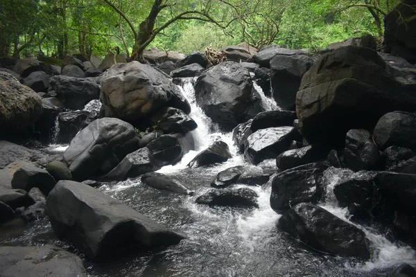 Un ruisseau d'eau tombant entre les rochers d'une rivière Images De Stock Libres De Droits