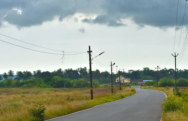 Hermosa carretera vacía en temporada de otoño con campos amarillentos y cielo nublado en Goa —  Fotos de Stock