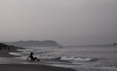 Sahilde dalgaların tadını çıkaran bir çocuğun siyah beyaz görüntüsü.