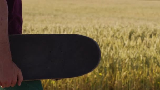 Erwachsene Gehen Neben Schönen Weizenfeld Mit Skateboard Mit Blauem Himmel — Stockvideo