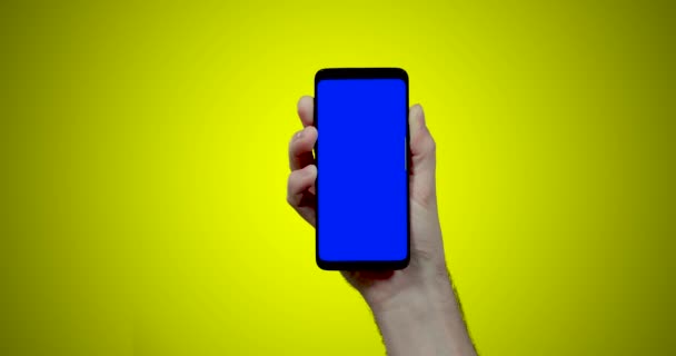 Man Hand Houden Smartphone Met Blauwe Chroma Toets Gele Achtergrond — Stockvideo