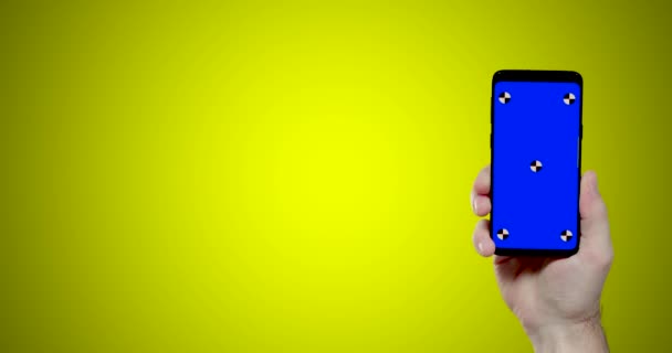 Sarı Arka Planda Mavi Krom Tuşlu Akıllı Telefonu Tutan Adam — Stok video