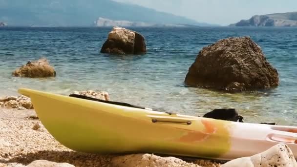 カヤックは クロアチアのKrk島の波で揺れる孤独なビーチ 美しい水と太陽に横たわっています — ストック動画
