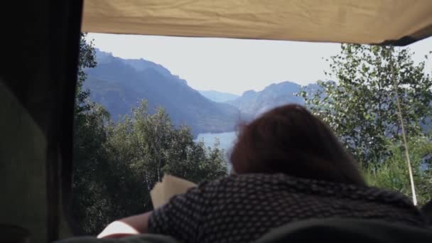 Молода Жінка Лежить Наметі Читаючи Книгу Красивому Фоні Озером Горами — стокове відео