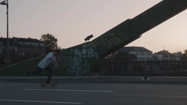 スケートボーダーがフランクフルトの高層ビルの前で橋を渡る4Kの夕日 — ストック動画