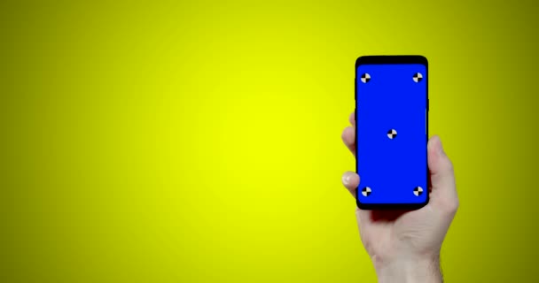 muž ruka drží smartphone s modrým chroma klíčových sledovacích bodů na žlutém pozadí přichází na pravé straně obrazovky