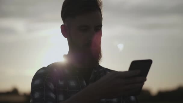 Homem Com Pão Escreve Mensagem Móvel Verifica Navegação Pôr Sol — Vídeo de Stock