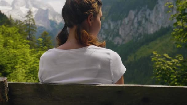 ゴサウジーオーストリア 若い女性はスローモーションでベンチの山の風景の上に座っている — ストック動画