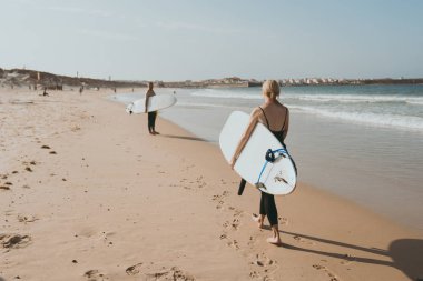 Bali sahilinde yürüyen sörfçüler