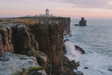 Lighthouse on the edge of a cliff big ocean waves crash on a rock Peniche Portugal