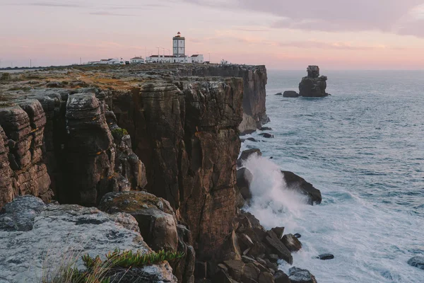 Lighthouse on the edge of a cliff big ocean waves crash on a rock Peniche Portugal