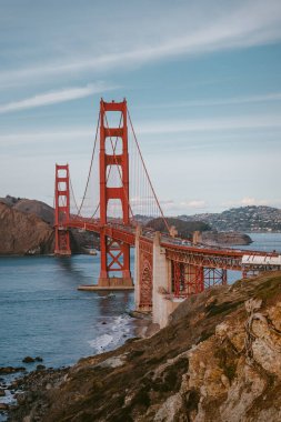 Gün batımında San Francisco 'da muhteşem bir milli anıtın ve tarihi Golden Gate Köprüsü' nün fotoğrafı. Dünyanın en ünlü köprüsünün altında küçük tekneler yelken açıyor.