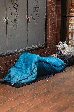 Evsiz Asyalı kadın San Francisco 'da mavi bir uyku tulumunun içinde kaldırımda uyuyor.