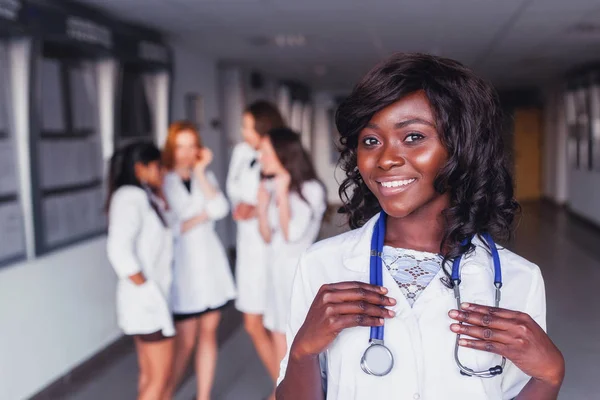 African medical student smiles at the university against the backdrop of a group of friends