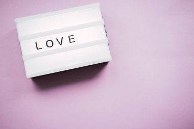 Pembe arka planda aşk sözcüğünün yazılı olduğu bağlama kutusu. Sevgililer Günü konsepti.