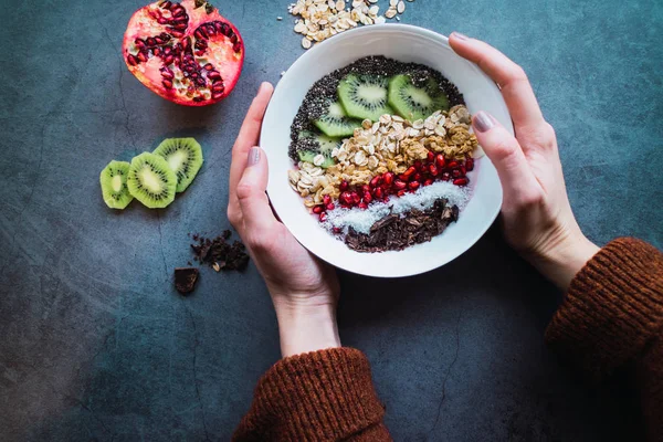 Café da manhã saudável: mãos de mulher segurando uma tigela de smoothie com cereais e frutas. Depósito plano . — Fotografia de Stock