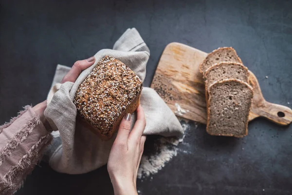 Mãos de mulher segurando um pão de trigo mourisco com chia. Vista superior . — Fotografia de Stock