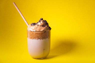 Çikolata parçalı Dalgona kahvesi ve sarı arka planda bambu kamışı. Kore buzlu kahvesi. Boşluğu kopyala.