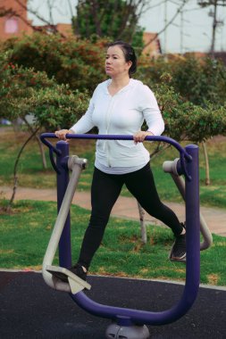 Kolombiyalı ve Latin Amerikalı kadın halka açık parkta makine kullanarak egzersiz yapıyor.