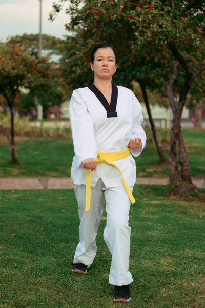 Colombiana, mujer latinoamericana practicando taekwondo con nunchakus defensa derecha abajo — Foto de Stock