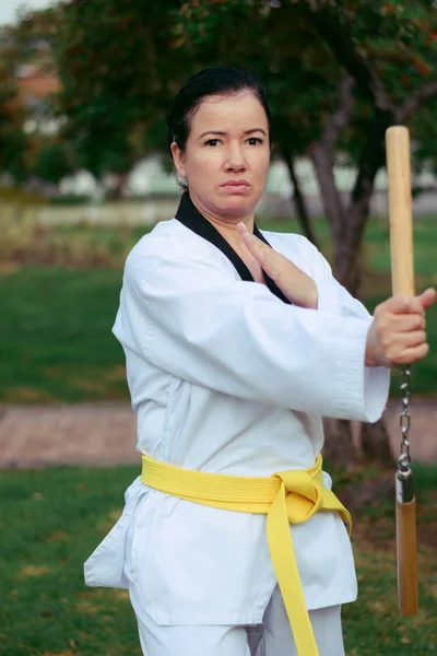 Colombian, Latin American woman practicing taekwondo with moving nunchakus, right hand