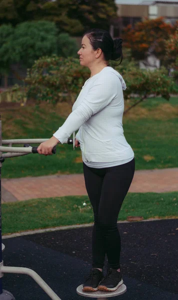Colombian and Latin American woman exercising in the public park using machines