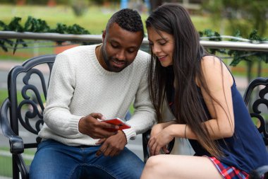 Mutlu adam ve kadın cep telefonlarını kontrol ediyor.