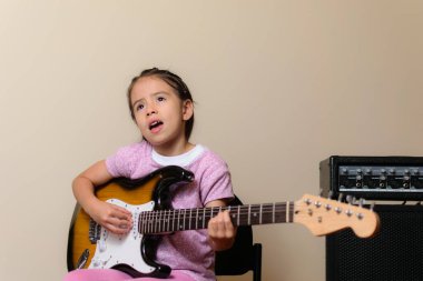 Güzel Latin Amerikalı Kolombiyalı kız elektro gitarıyla müzik çalışıyor.