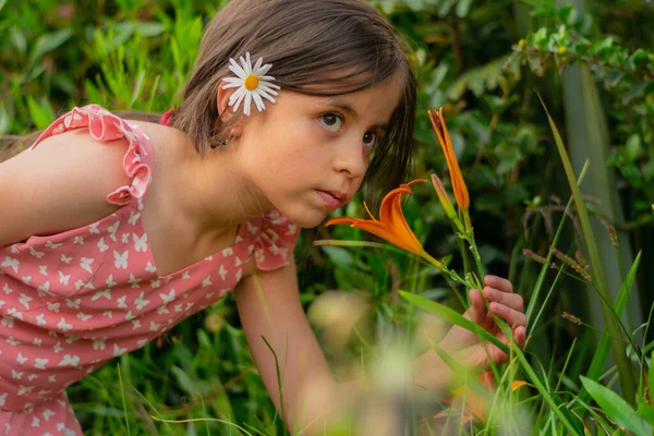 Long-haired Colombian girl smells the flowers of the garden in the spring — Stock Photo, Image