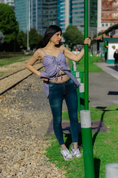 Κολομβιανή γυναίκα σε σταθμό τρένου περιμένει την άμαξα να παίζει στις ράγες. — Φωτογραφία Αρχείου