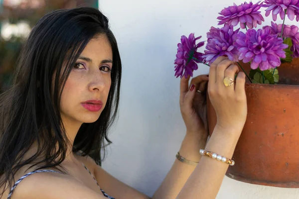 Mujer colombiana de pelo largo huele y acaricia flores de jardín en la primavera —  Fotos de Stock