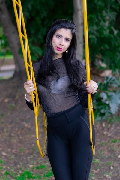 Mujer colombiana disfrutando de una tarde soleada en el parque de la ciudad jugando en el columpio —  Fotos de Stock