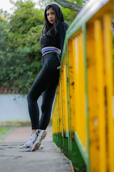 Mujer colombiana disfrutando de una tarde soleada en el parque de la ciudad pasa por un puente para volver a casa —  Fotos de Stock