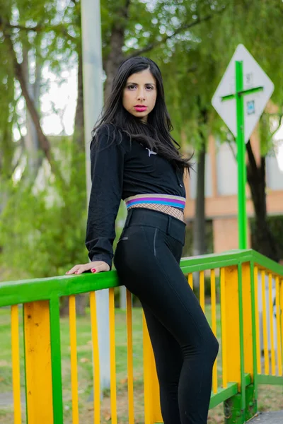 Mulher colombiana desfrutando de uma tarde ensolarada no parque da cidade passa por uma ponte para ir para casa — Fotografia de Stock