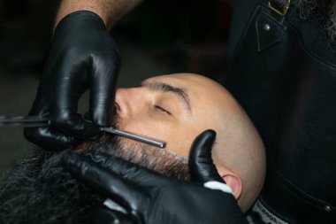 Bogota şehrinde uzun sakallı bir Latin Amerikalı berber çalışıyor.