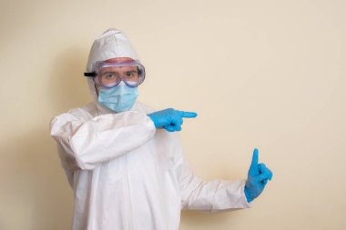 Beyaz koruyucu takım elbiseli, gözlüklü ve ameliyat eldivenli Latin bir adam koronavirüsü kapmamak için.)