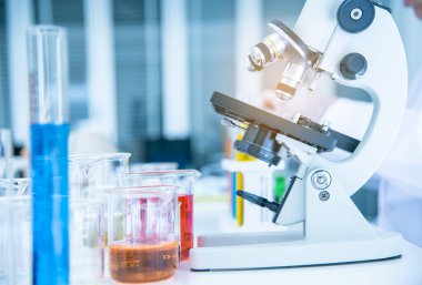 Mikroskop ve test tüpleri, bilim laboratuarında kimyasallar içeren cam kaplar..