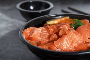 Siyah bir kasede yumurtayla kaplanmış taze somon balığı, siyah soslu yeşil deniz yosunu serpiştirilmiş, mermer masa arkasında Asya 'da popüler..