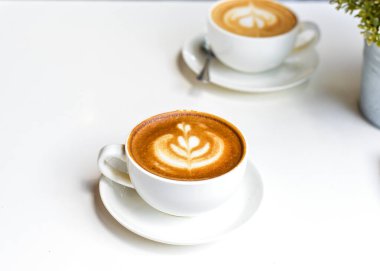 Kahve dükkanındaki beyaz çiçek desenli kahve beyaz bir arka planda.