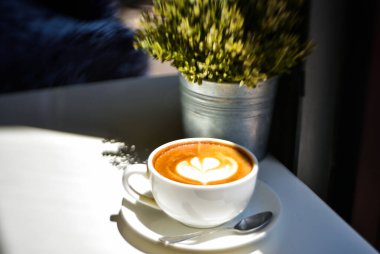 Kahve dükkanındaki beyaz çiçek desenli kahve beyaz bir arka planda.