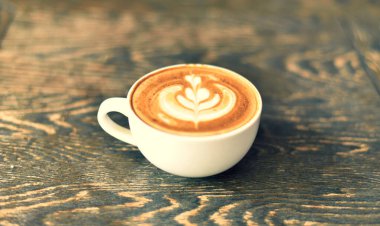 Kahve dükkanındaki ahşap masada beyaz bir fincanda kahve.