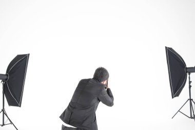 Asyalı profesyonel fotoğrafçı şirketin stüdyosunda beyaz arka planda ışıklandırma ekipmanıyla fotoğraf çekmeye hazırlanıyor. İmaj satışı konsepti günümüzde popüler..