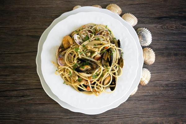 Спагетти с морепродуктами в белой керамической тарелке на деревянной бэкгру — стоковое фото