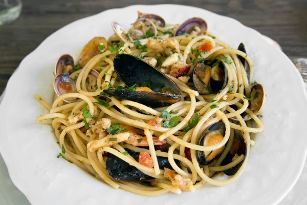 Спагетти с морепродуктами в белой керамической тарелке на деревянной бэкгру — стоковое фото